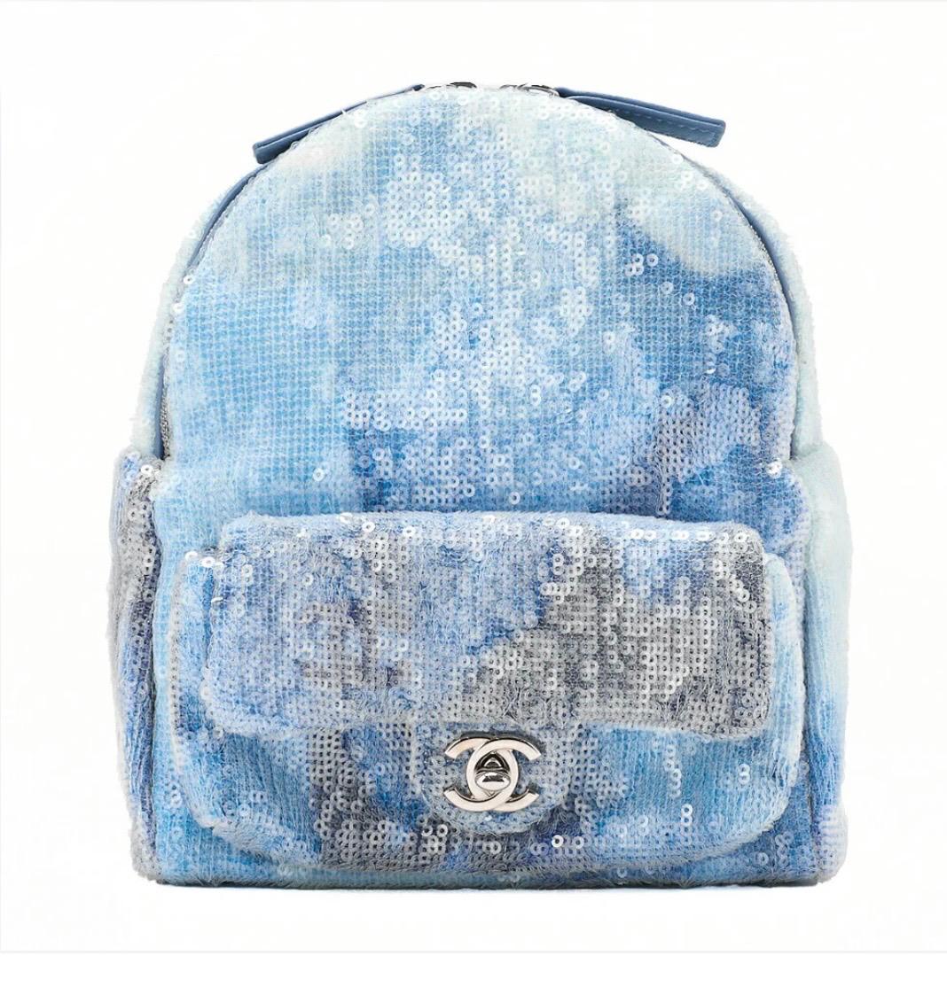 Sac à dos CHANEL à sequins bleus multicolores avec logo Coco et finitions argentées, modèle luxe d’occasion rare.